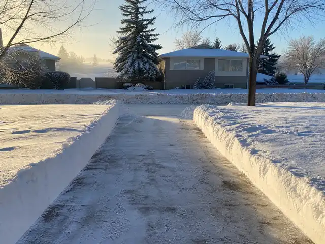 A residential driveway cleared of deep snow on a winter morning in Saskatoon, SK